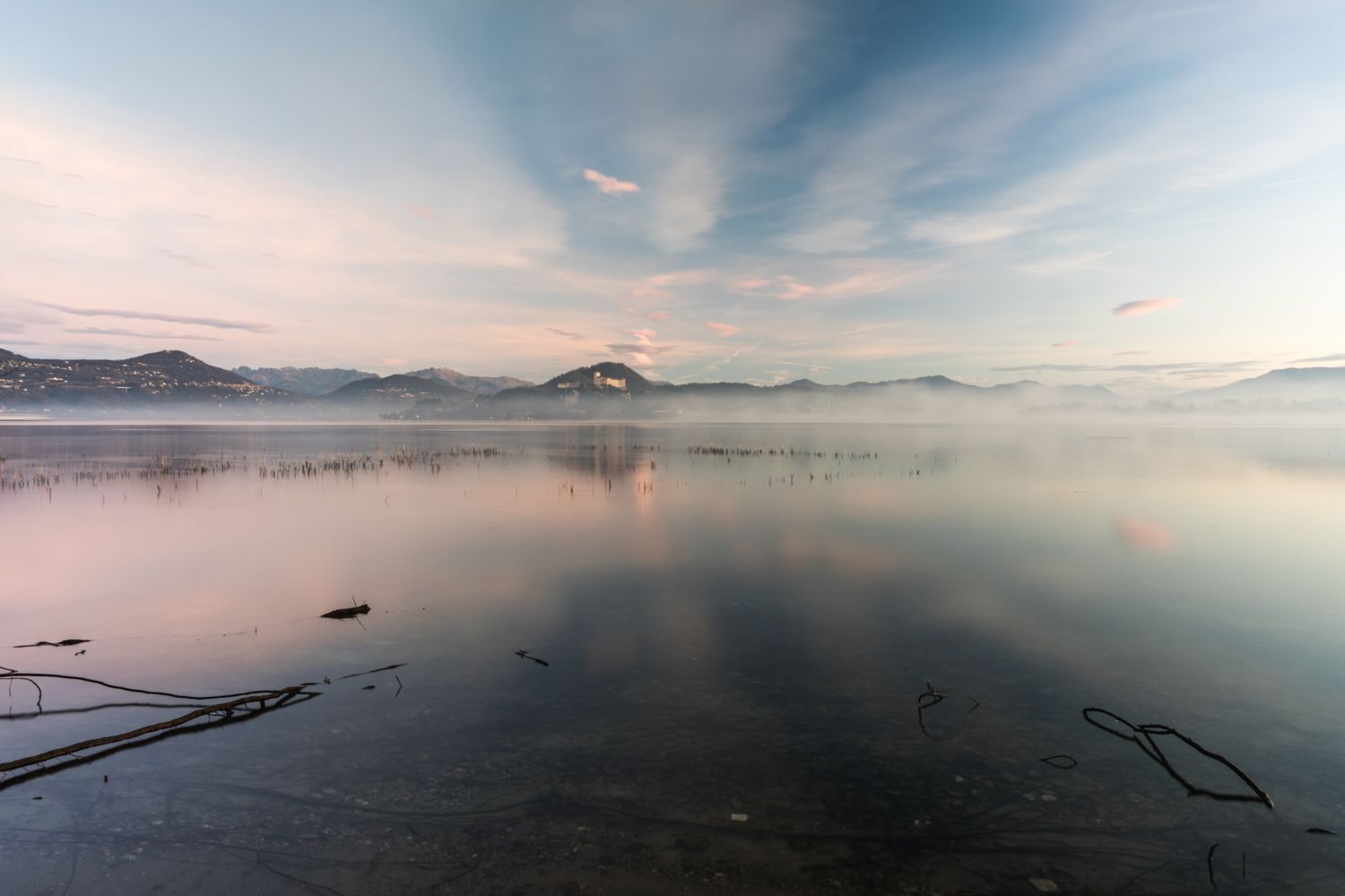 Still lake at dawn with low mist drifting across the water