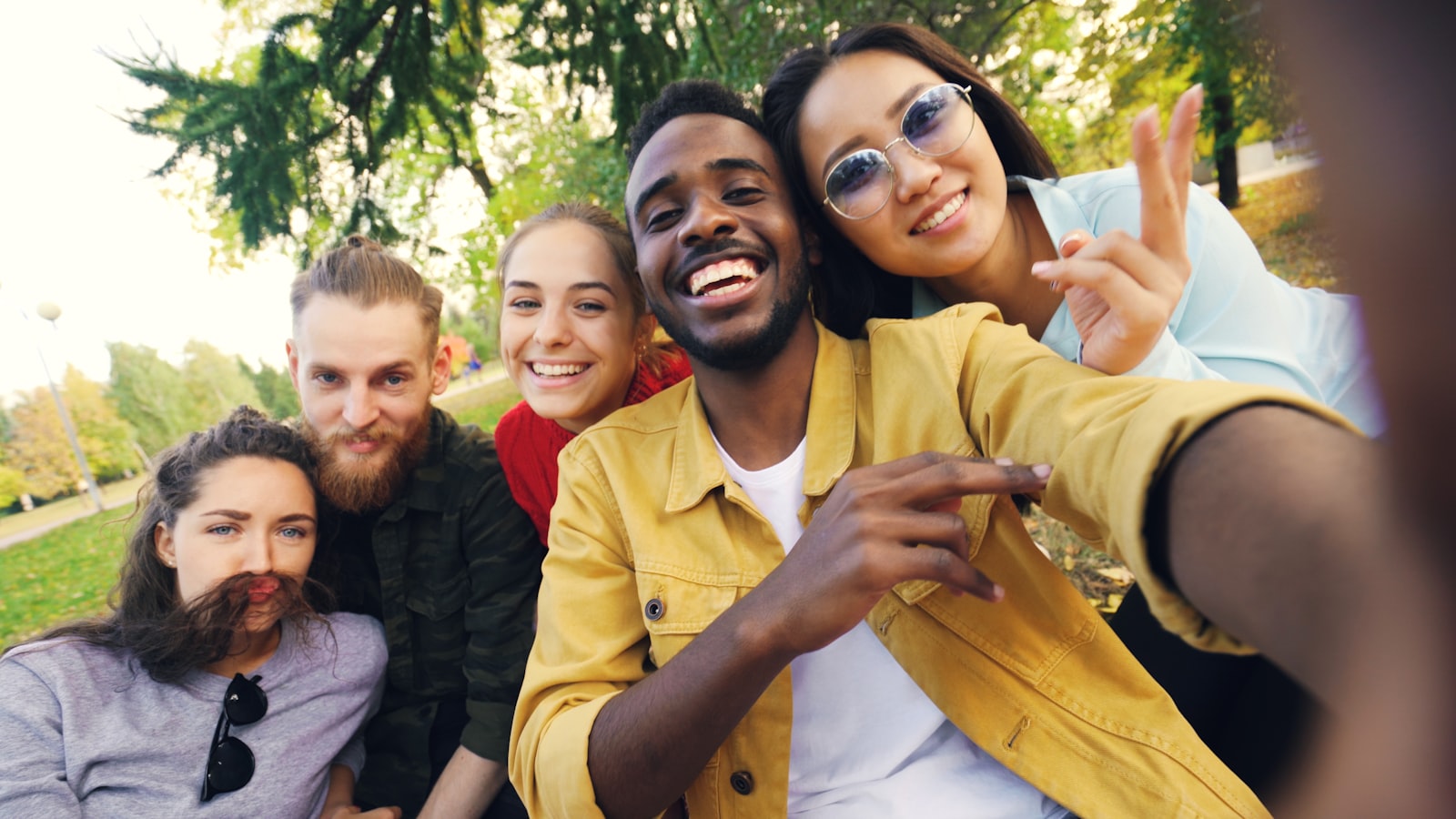 A diverse group of people smiling together in warm light, illustrative of the range of Tampa adults who start trauma therapy.